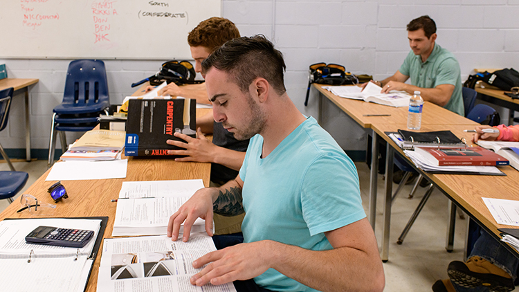 Georgian-Muskoka-construction-trades-pre-apprenticeship-students-flip-through-pages-of-textbook-in-classroom