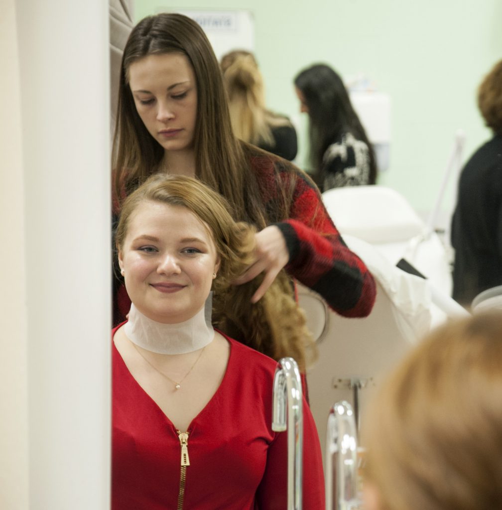 发型的学生在镜子里做一个年轻女子的头发
