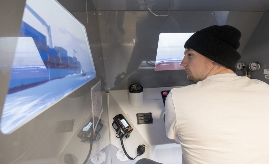 年轻人戴着脚趾并在海洋模拟器中驾驶一艘船