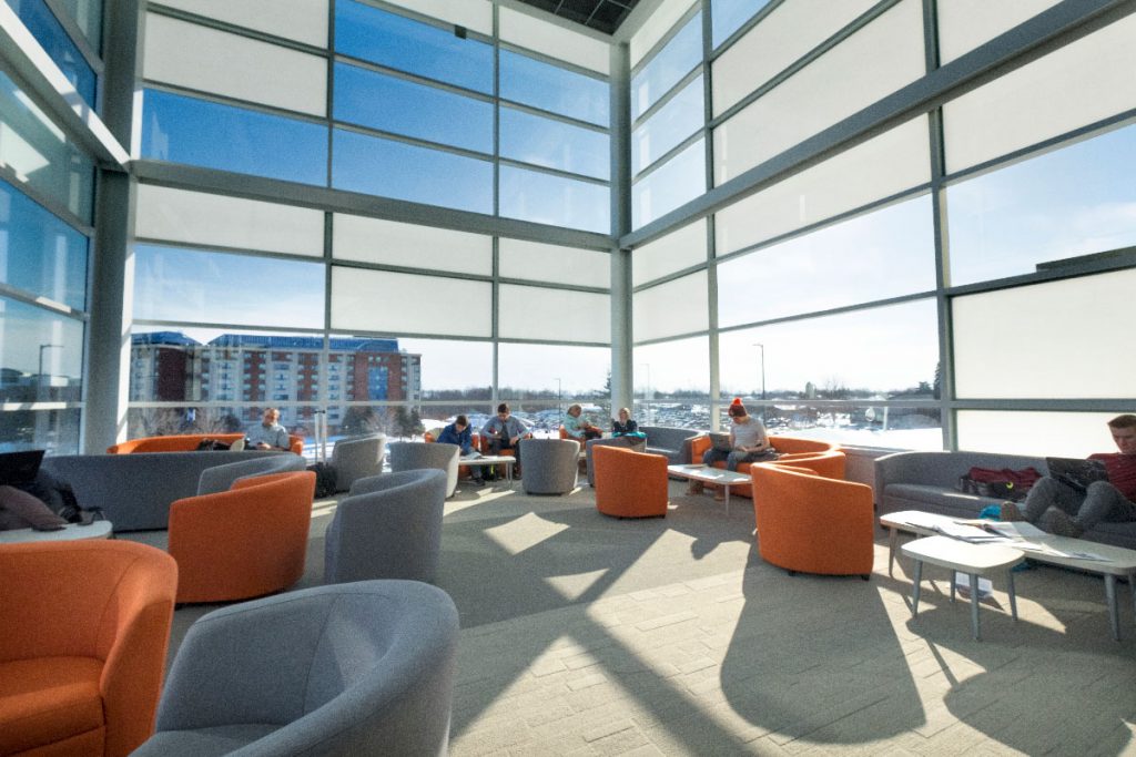 格鲁吉亚学院巴里校区先进技术研究中心的学生休息室空间的建筑照片，以橙色和灰色的躺椅和天花板高的窗户为特色必赢彩票首页苹果官方版