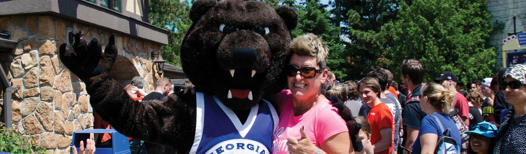 咆哮者，格鲁吉亚灰熊的吉祥物，站在校友旁边在加拿大的仙境格鲁吉亚日