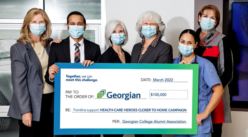 六个人穿着商务装，戴着口罩举着一张10万美元的乔治亚学院大额支票必赢彩票首页苹果官方版