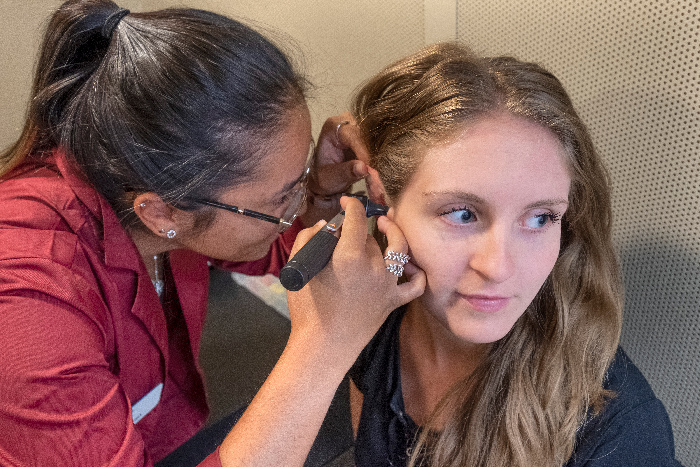 沟通障碍助手使用耳镜观察另一名学生的耳朵