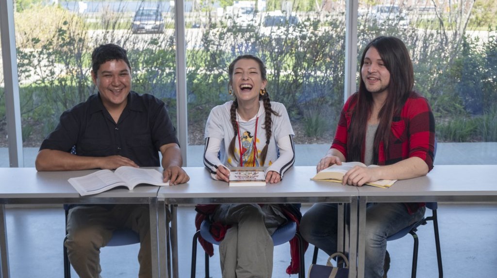 三个土著学生坐在一张桌子前，面前放着书