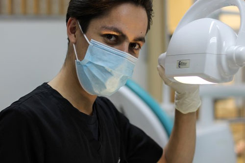 牙科保健师的学生戴着面罩，坚持光照