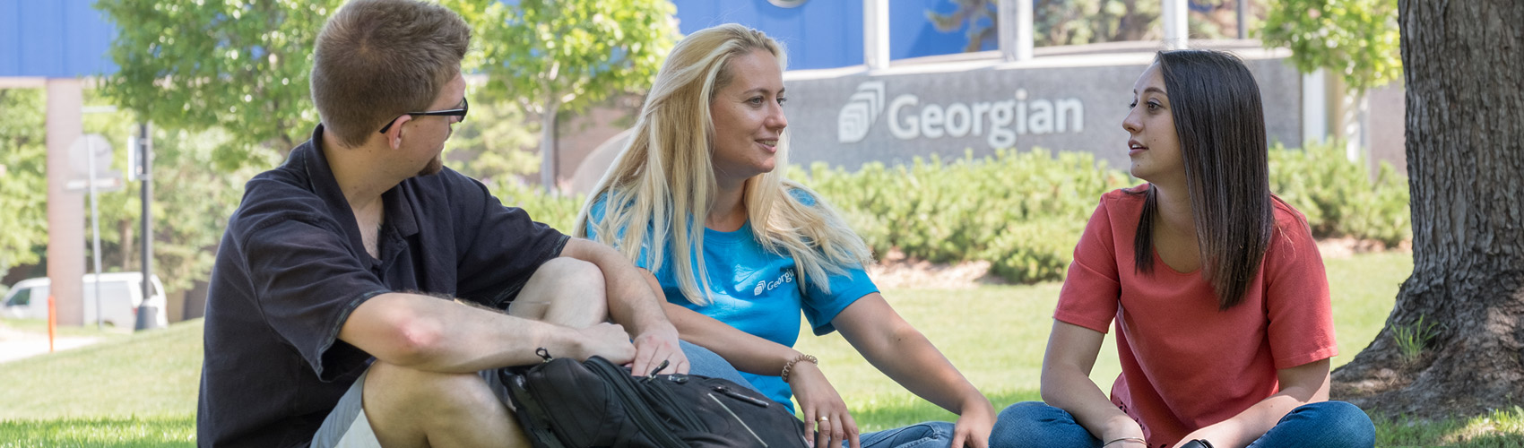 一名男学生和两名女学生坐在乔治亚学院巴利校区主入口前的草地上必赢彩票首页苹果官方版