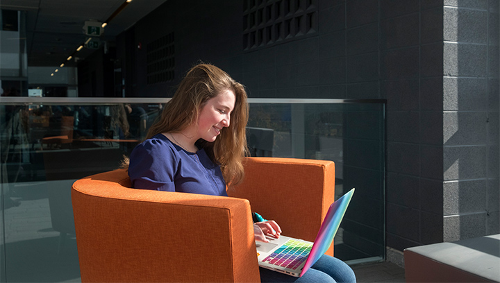 一名学生坐在巴里校区N楼的橙色躺椅上使用笔记本电脑